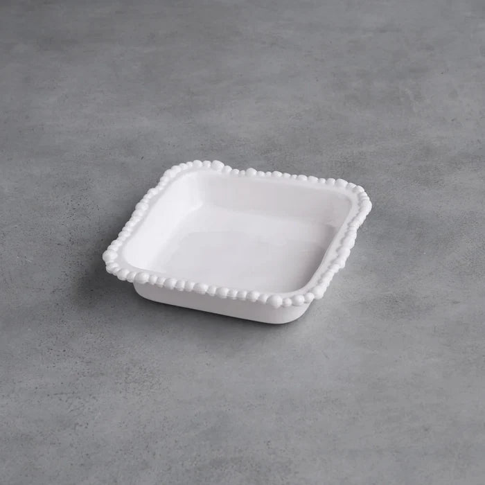 White ceramic dish with decorative edge on a gray concrete surface