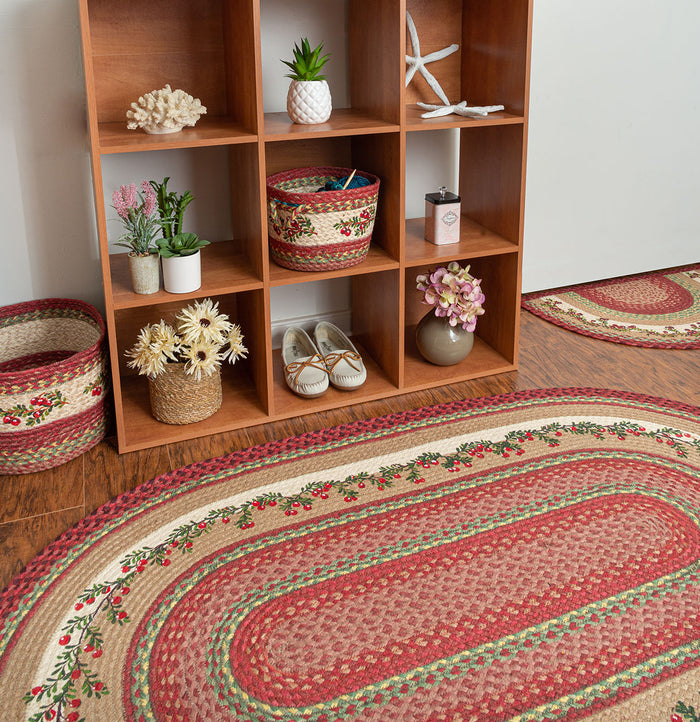 Braided rug with cranberries border design in red, green, and tan colors made from braided jute.