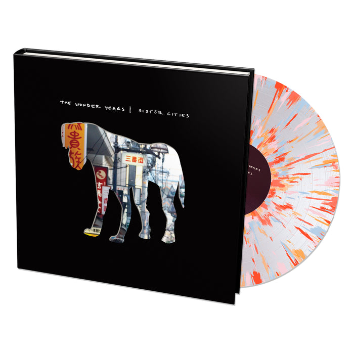 A Limited Edition vinyl with a white and orange splatter design is partly out of its black sleeve, which shows an elephant silhouette filled with an urban scene and The Wonder Years | Sister Cities text.