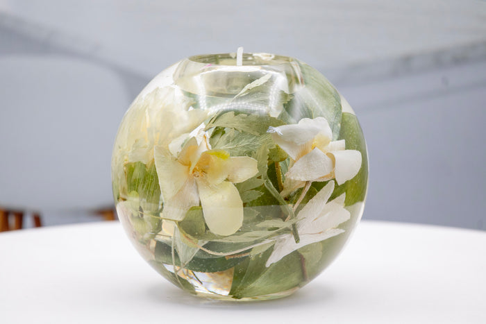Tall portrait photo of a pressed flower tealight candle sphere with mixed dried botanical layers