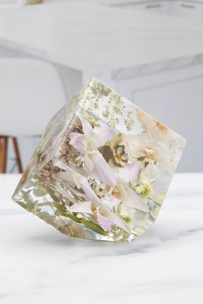 Resin geometric display with embedded orchid preserved flowers on a white surface
