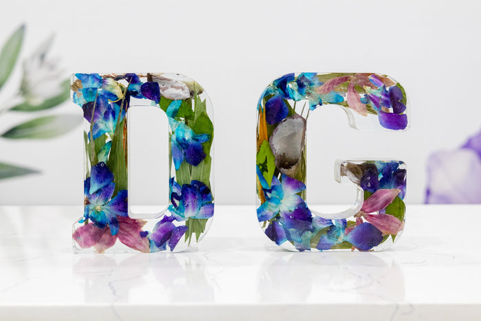 Landscape photo of a pressed flower letter block with cream dried botanicals on a countertop