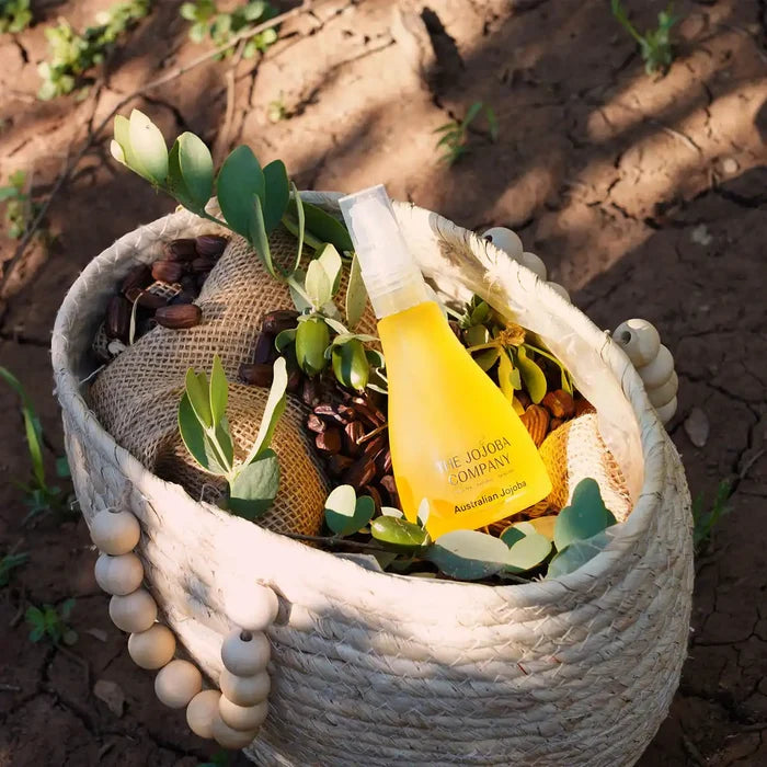 Yellow 85ml bottle of Australian Jojoba Oil in a woven basket with plants on a natural background