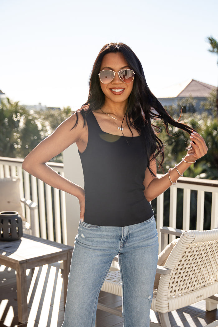 Woman wearing sunglasses and a black tank top on a balcony