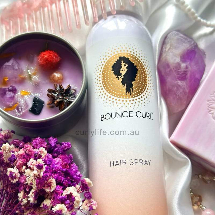 Bounce Curl Hair Spray with purple flowers, amethyst crystal, and pink candle for curly hair care