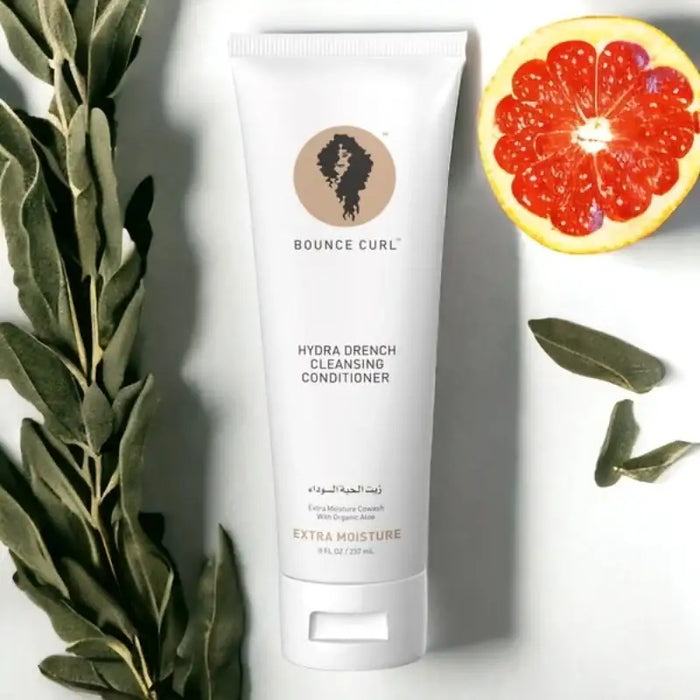 Bounce Curl Hydra Drench Cleansing Conditioner with organic aloe, surrounded by green leaves and grapefruit slice