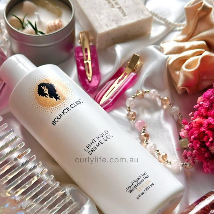Bounce Curl Light Hold Creme Gel for defined curls, styled with hair clips, silk scarf, and accessories on satin