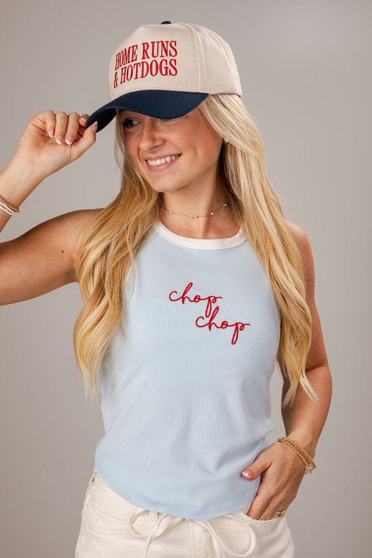 Woman wearing a cap and tank top with text, against a plain background