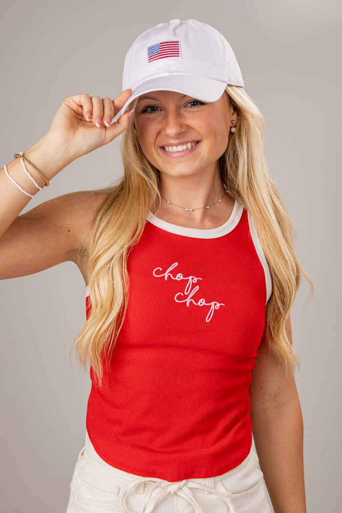 Woman wearing a red tank top with 'chop chop' text and a white cap with an American flag on a gray background
