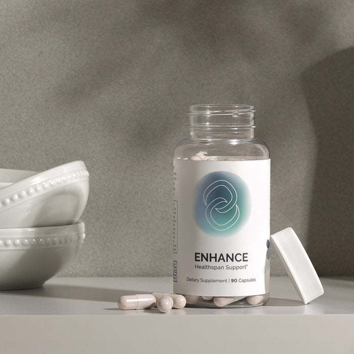 InfiniWell ENHANCE Healthspan Support dietary supplement bottle with open lid and capsules on display, 90 capsules.