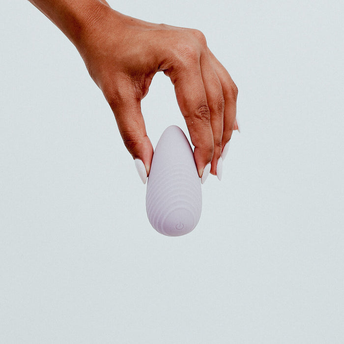 Hand holding Viola Green Eros Palm Vibrator in Lilac colour, a small, palm-sized vibrator. Powerful vibrations, effortlessly controlled with a single button. Its grip-friendly design ensures a comfortable and pleasurable experience. Its discreet size also makes it the perfect travel buddy. It's crafted from sustainable materials, such as super silky body-safe silicone and is designed to combine sophistication with eco-consciousness, making it the perfect companion for sustainable pleasure seeker