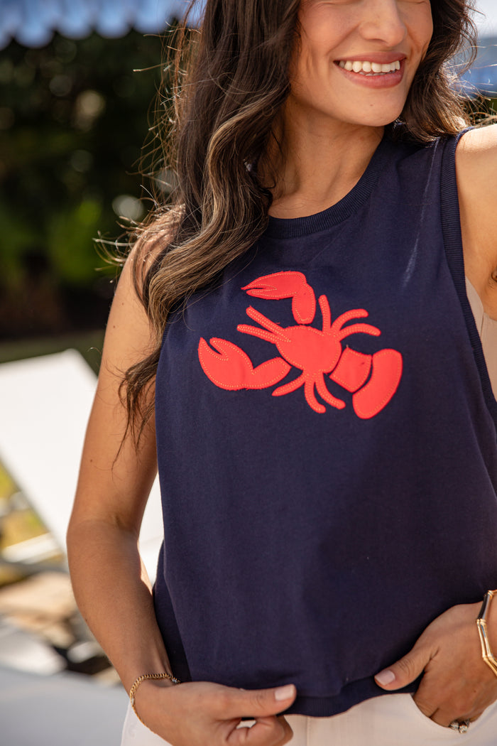 Woman wearing a navy blue sleeveless shirt with a red crab design outdoors.