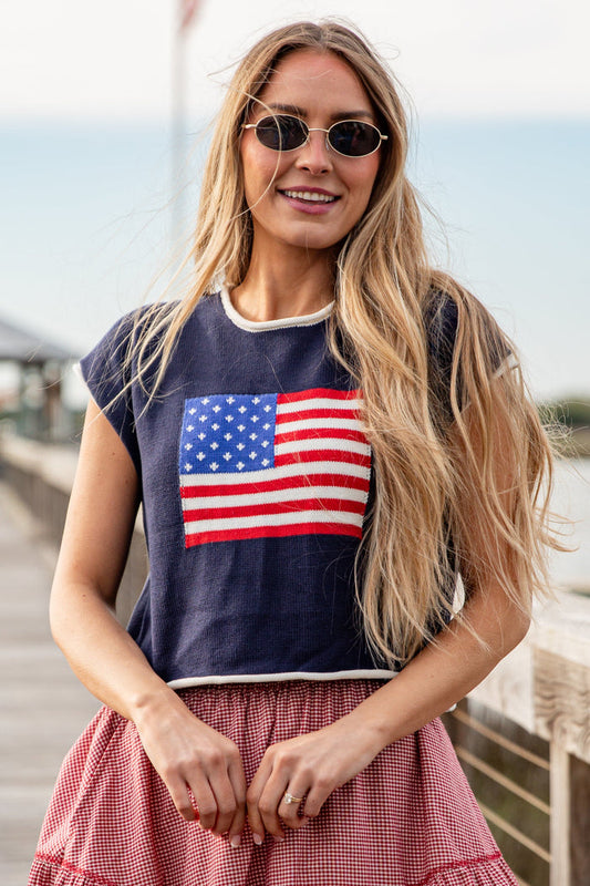 Woman wearing a navy blue t-shirt with an American flag design, standing on a wooden dock.