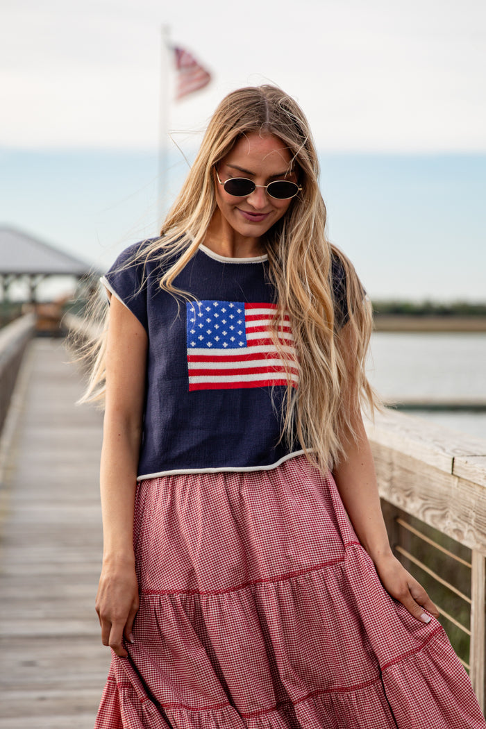 Woman wearing a t-shirt with an American flag design on a wooden dock.