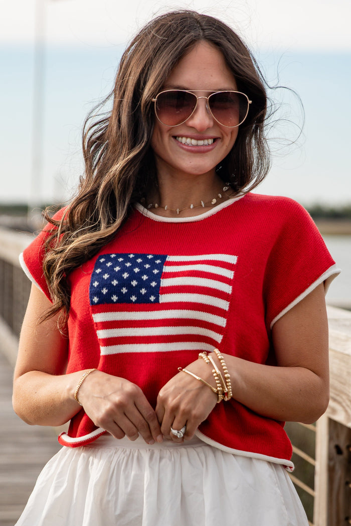 Woman wearing a red shirt with an American flag design outdoors.