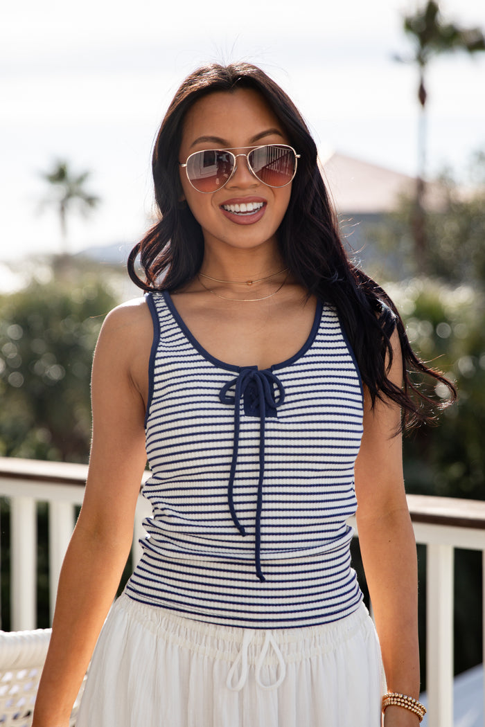 Woman wearing a striped tank top and sunglasses outdoors