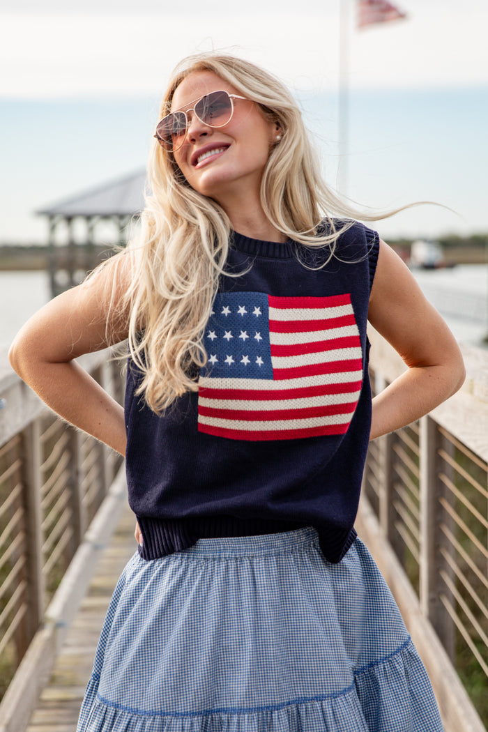 Woman wearing a sleeveless top with an American flag design on a dock.