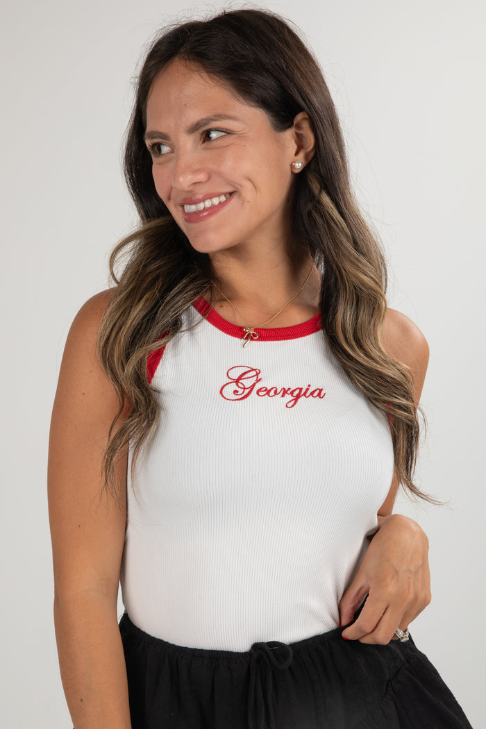 Woman wearing a white tank top with red accents and 'Georgia' text on a plain background