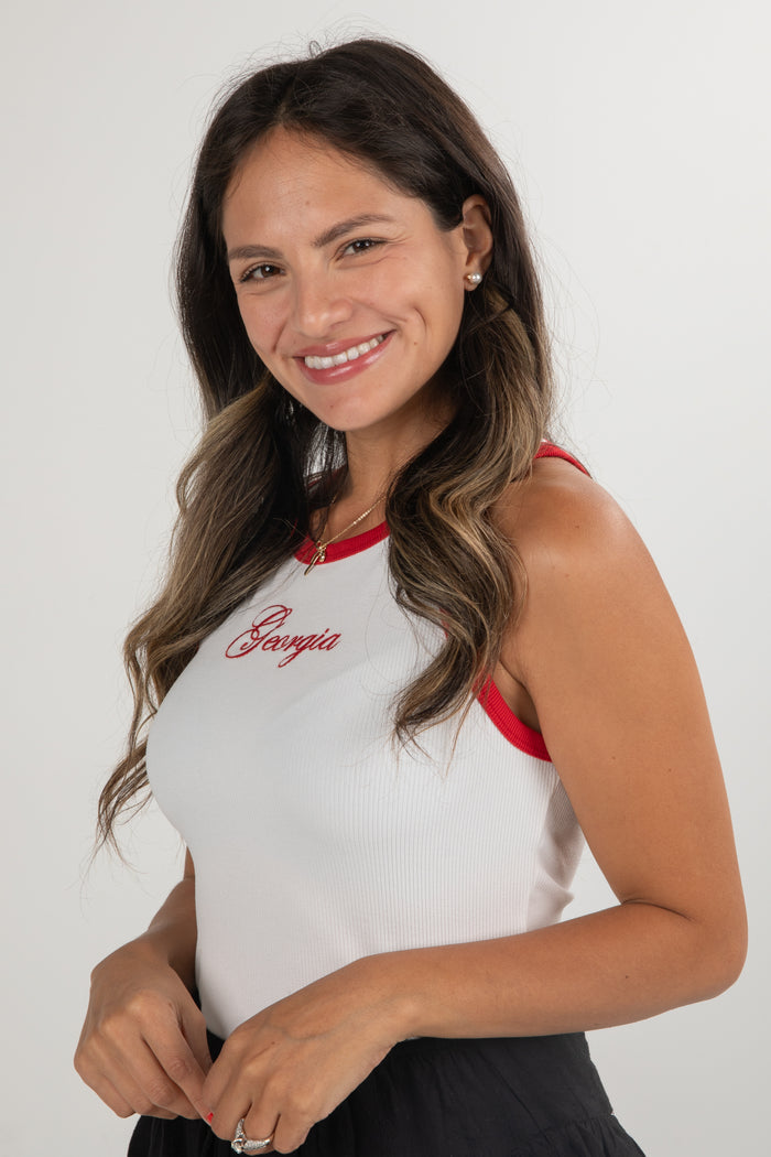Woman wearing a white tank top with red accents and 'Pamela' branding on a plain background