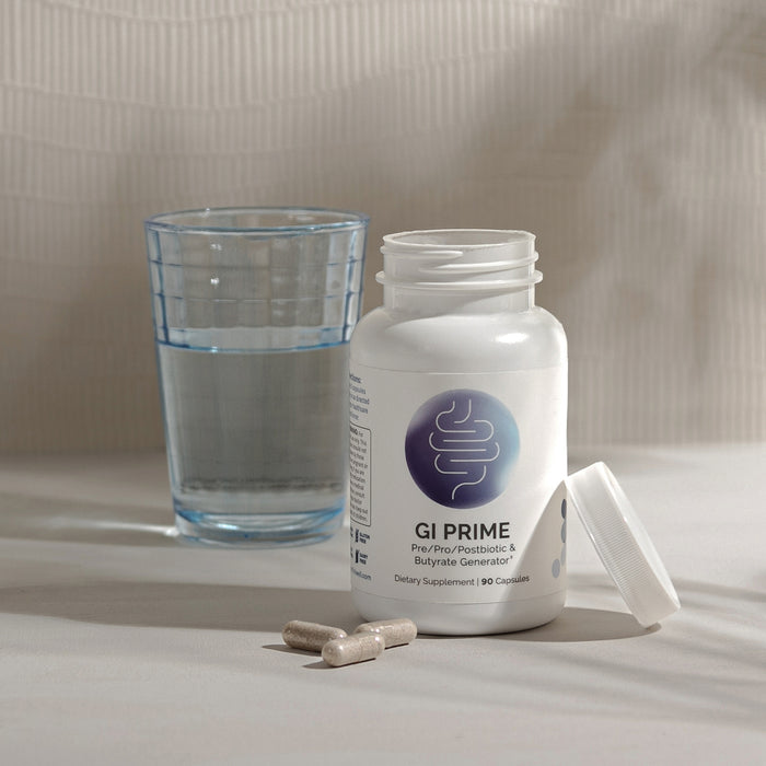 InfiniWell GI PRIME dietary supplement bottle with capsules beside a glass of water, 90 capsules.
