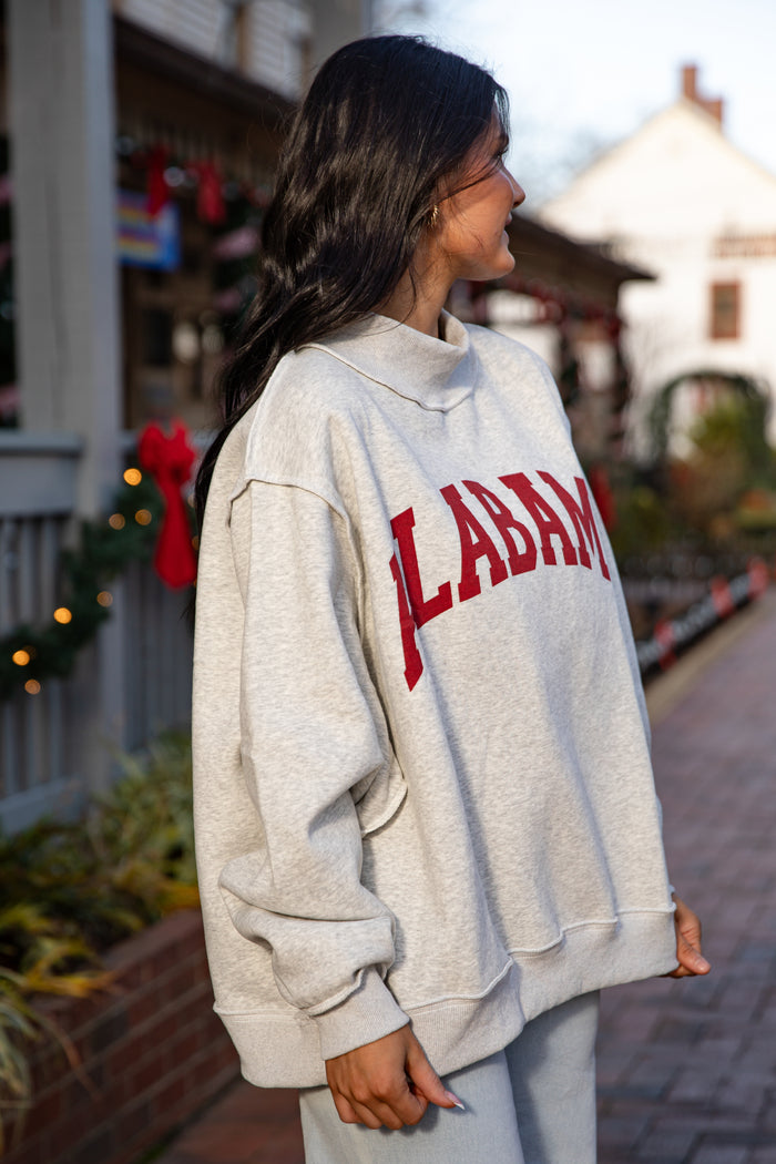 Person wearing a hoodie with 'Alabama' printed on it, standing outdoors.