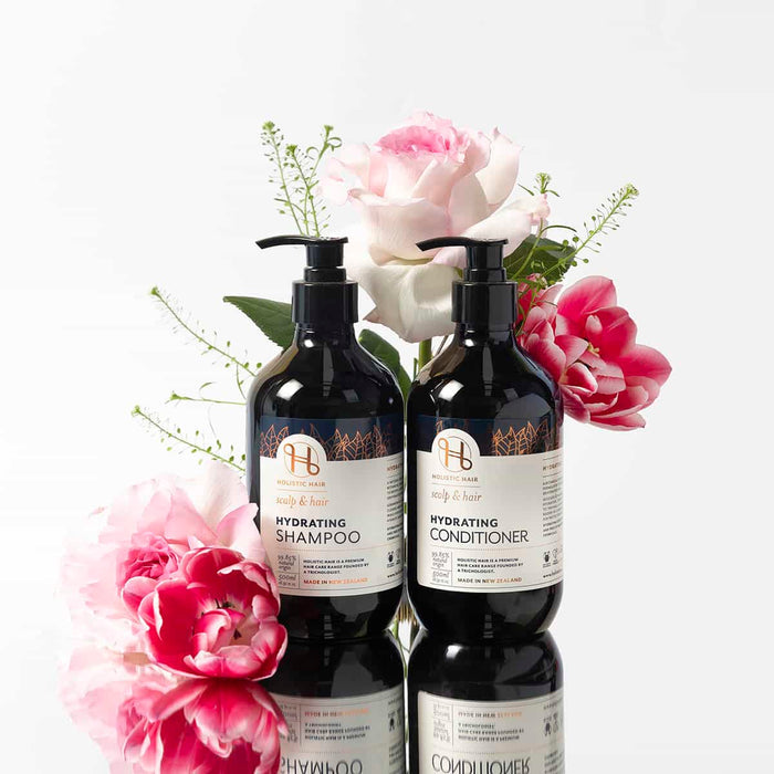 Two bottles of 'Hydrating Shampoo' and 'Conditioner' with flowers on a white background.
