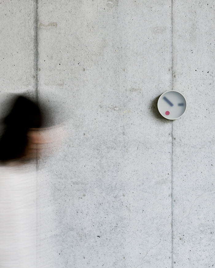 In situation image of Gray Kehai Clock by Koizumi studio on concrete wall.