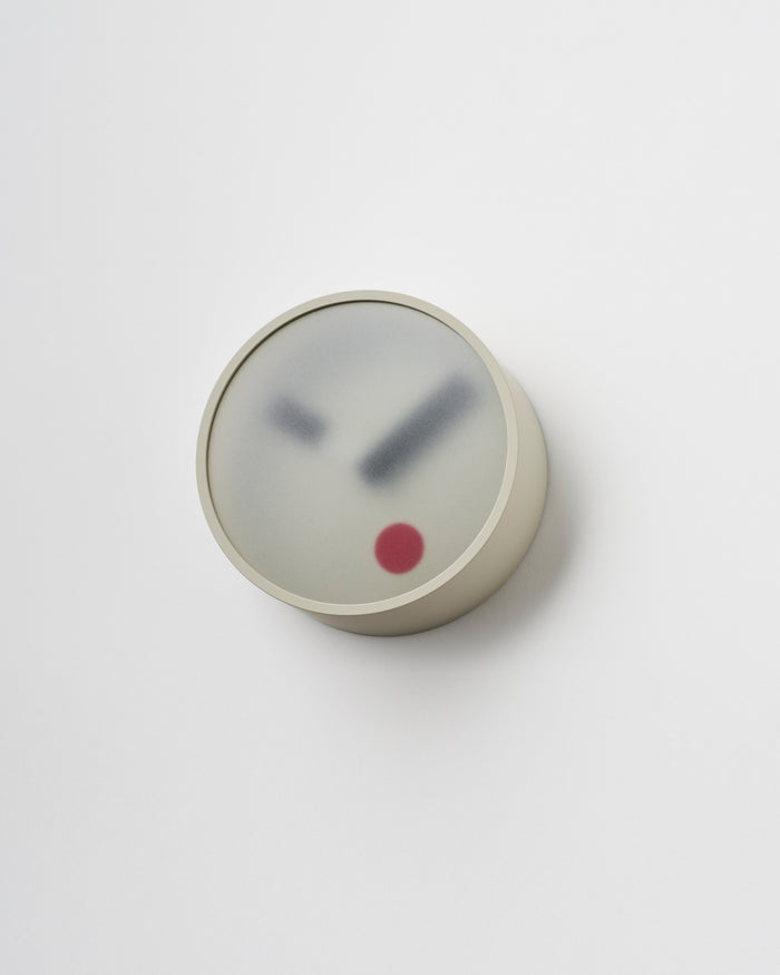 Angled side view of Gray Kehai Clock by Koizumi studio against white-gray background.