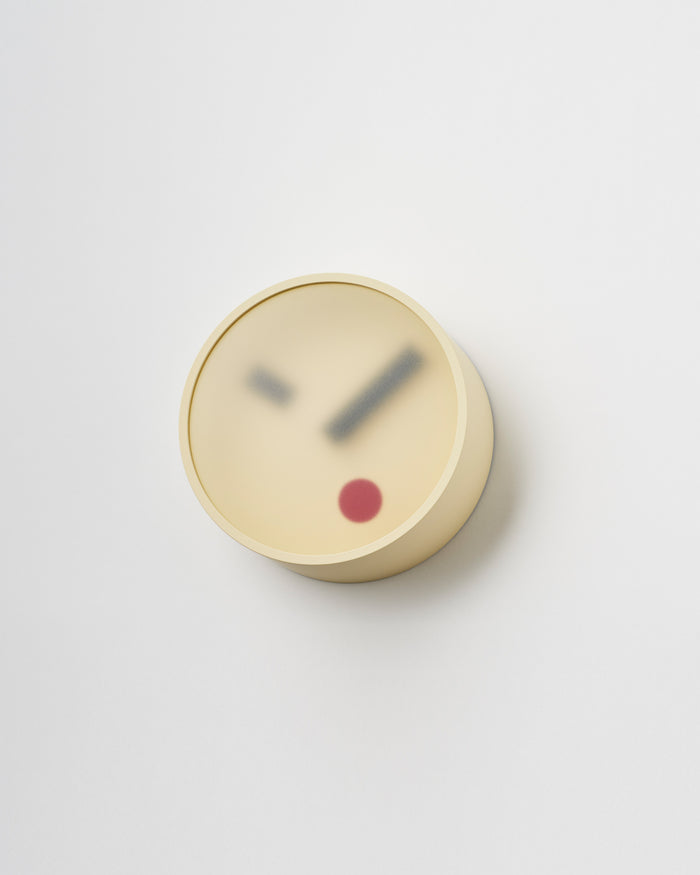 Angled side view of Yellow Kehai Clock by Koizumi studio against white-gray background.