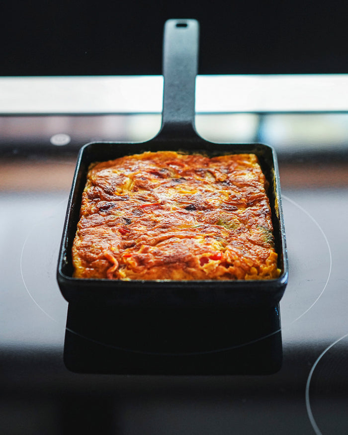 Rectangular cast iron egg pan by Oigen with baked dish on a stovetop