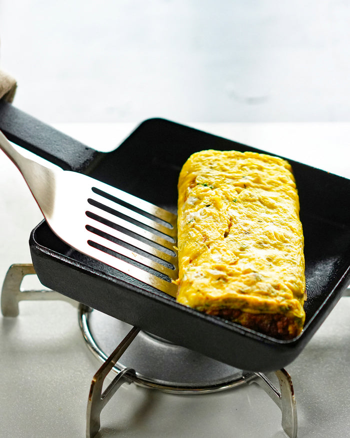 Omelette being scooped with a spatula from a cast iron pan by oigen