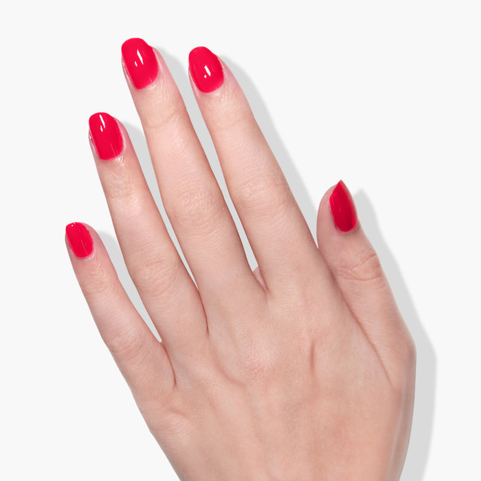 A hand with neatly manicured nails is painted with bright red LONDONTOWN London Calling vegan cruelty-free nail polish against a white background.