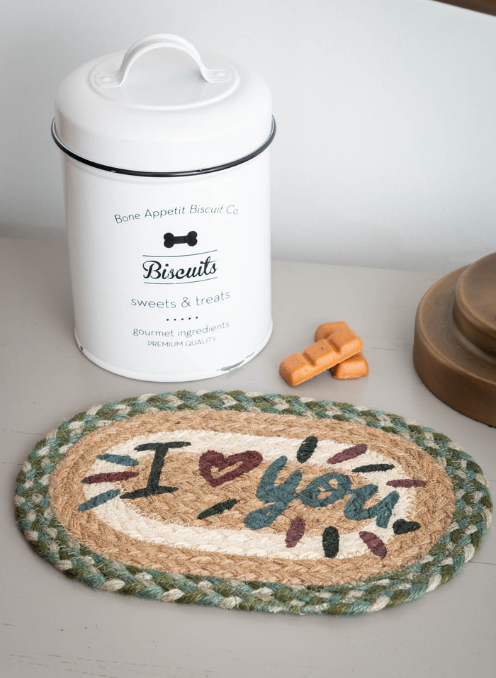 Pet placemat or trivet with "I love you" text with a metal tin of dog biscuits.