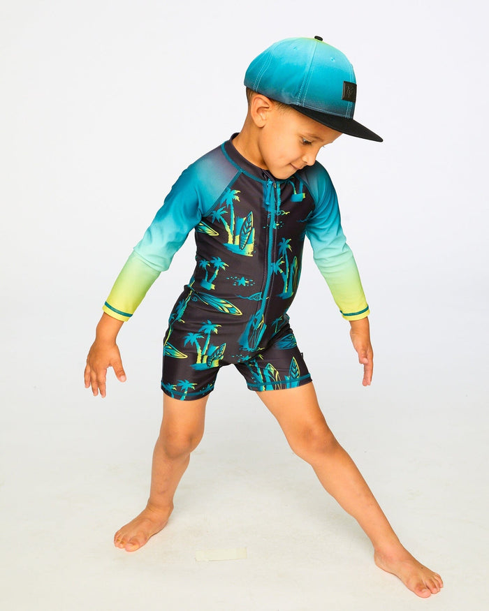 Boy posing in studio in black surf long sleeve rashguard romper front view