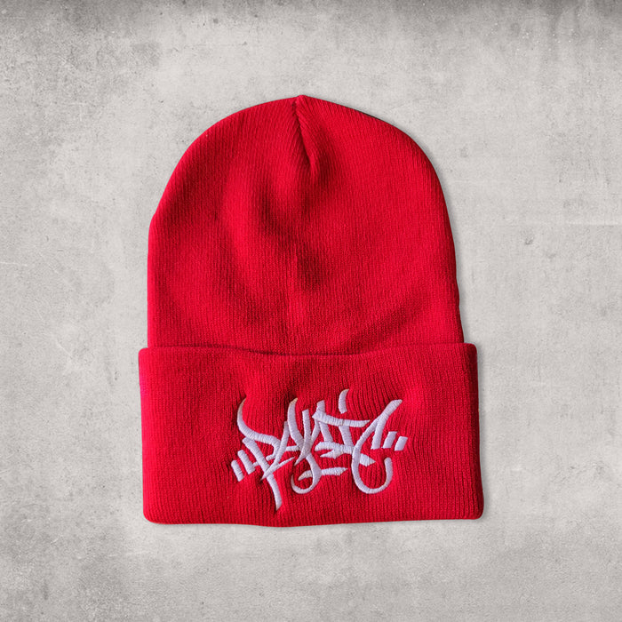 Red beanie hat with a white centered embroidery reading Panic in a tag font