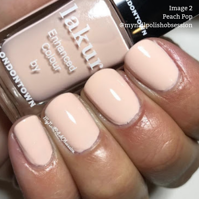 Close-up of a hand with nails painted in a peach color. A partially visible bottle of LONDONTOWN Lakur Enhanced Colour vegan nail polish labeled "Peach Pop" is held between fingers. "Image 2 Peach Pop" text overlays the image.