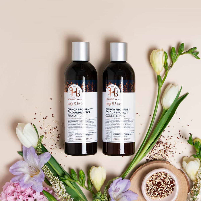 Two bottles of hair care products with flowers on a beige background.