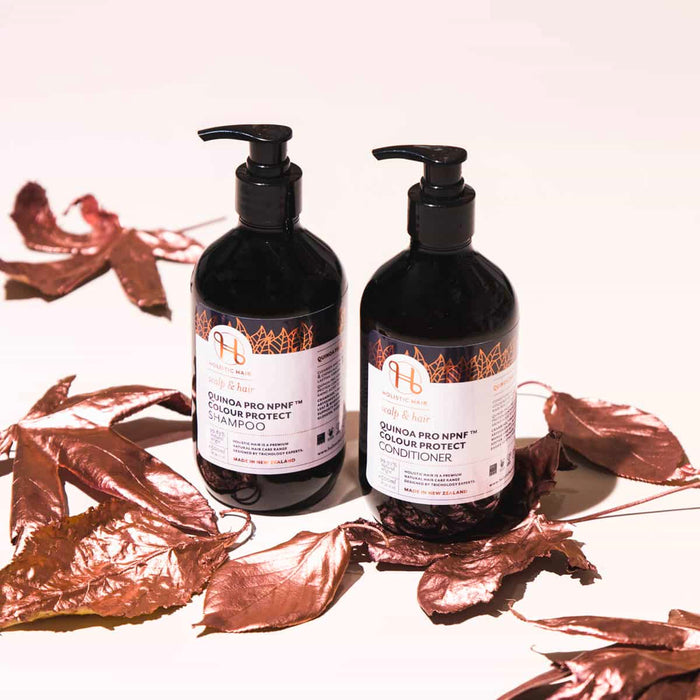 Two bottles of shampoo and conditioner with labels on a white background with brown leaves.