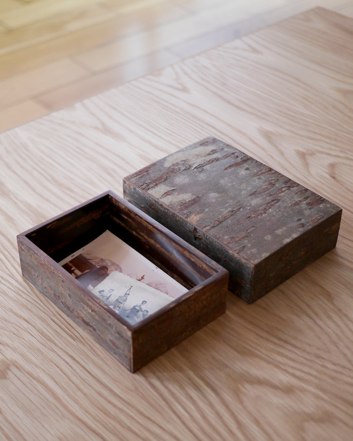 Open wooden box with lid by Denshiro showing vintage photos on a wooden surface