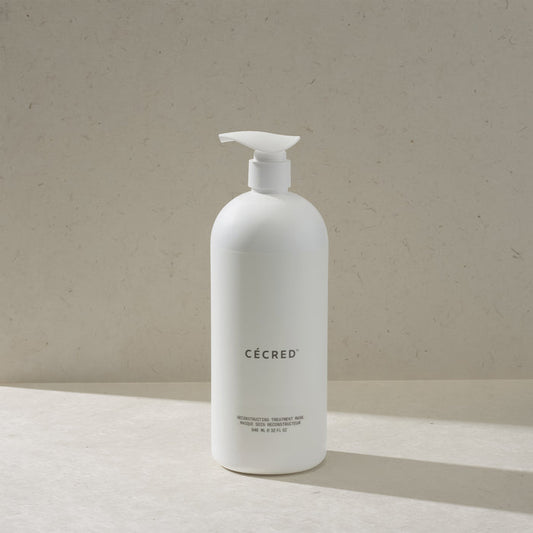 Cécred Reconstructing Treatment Mask in the max size pump bottle, standing on a beige surface against a tan textured background
