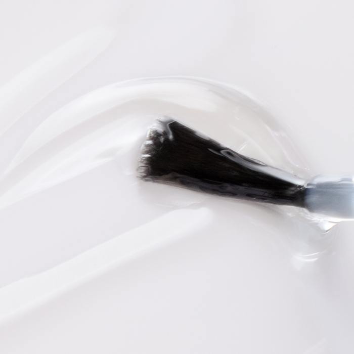 83143 SECHE VITE Quick Dry Top Coat 14ml | A close-up of a black nail polish brush applying clear glossy Seche Vite transparent topcoat to a white surface.