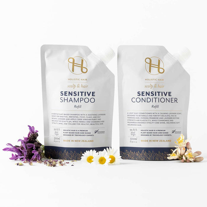 Holistic Hair Sensitive Shampoo and Conditioner refill packs with flowers on a white background