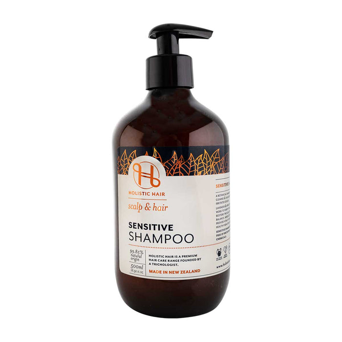 A bottle of Holistic Hair sensitive shampoo with a pump dispenser, predominantly dark brown in colour with a white label featuring plant imagery and text.