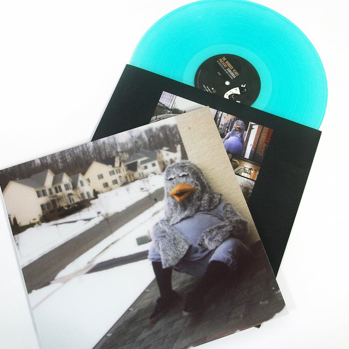 A turquoise vinyl record by The Wonder Years slides out of its sleeve, which shows someone in a bird costume on a snowy suburban rooftop, embodying true Hoodie Weather vibes amid houses and a wintry street.