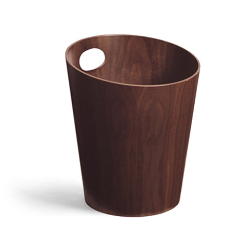 Silhouetted image of walnut paper waste basket with handle by Isamu Saito against white background.