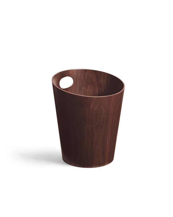Silhouetted image of walnut paper waste basket with handle by Isamu Saito against white background.