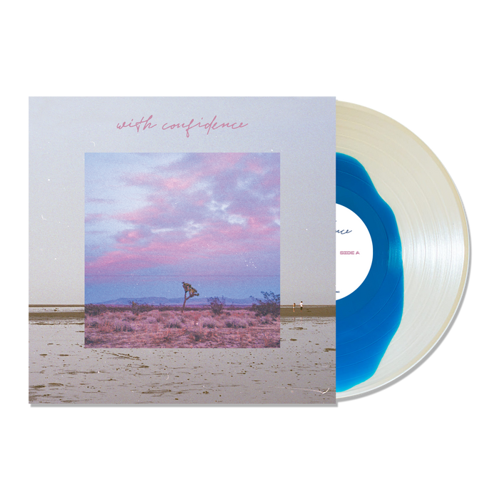 A Blue Inside Clear Variant vinyl by With Confidence is partially slid from its album cover, which displays a desert landscape beneath a pink and blue sky. With Confidence appears in pink cursive at the top.
